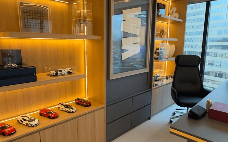 Sala do Dr. Sandro Ferraz: mesa de atendimento, poltrona e prateleiras iluminadas com miniaturas de carros